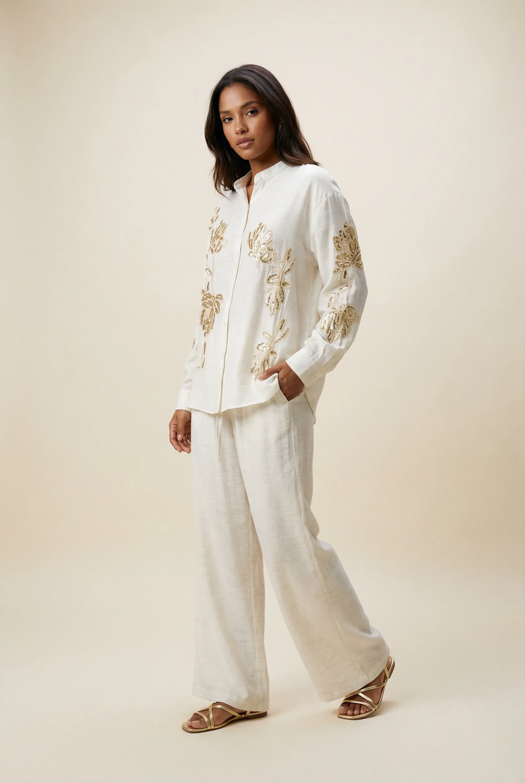 Generated with Kive.ai – young latin model in . she should wear flat gold strappy sandals. pants should reach the floor and sleeves should be till her wrists. product photo with a nice pose